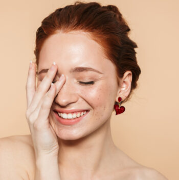 Portrait of a laughing pretty happy smiling amazing young redhead woman posing isolated over beige wall background.